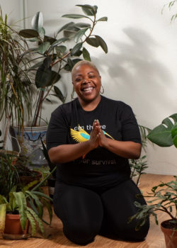 Black woman kneeling and surrounded by green plants