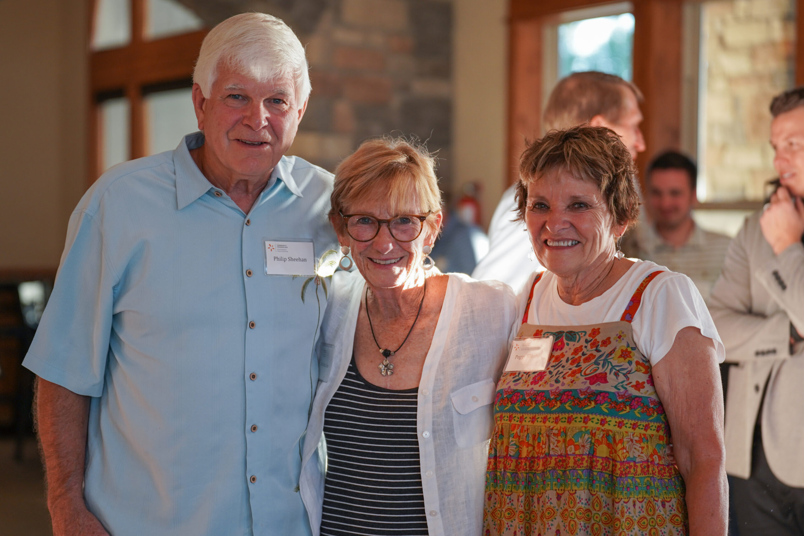 Three donors pose and smile into the camera during our annual supporter appreciation event.